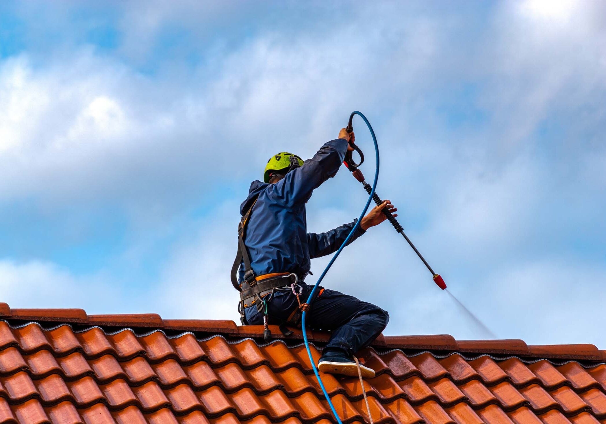worker washing the roof with pressurized water